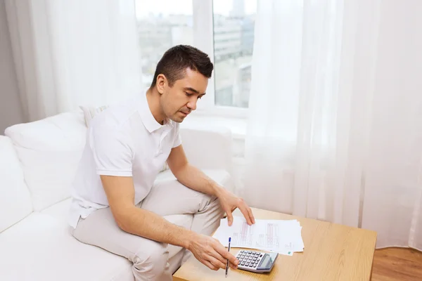 Homme avec des papiers et calculatrice à la maison — Photo