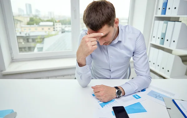 Stressad affärsman med papper i office — Stockfoto