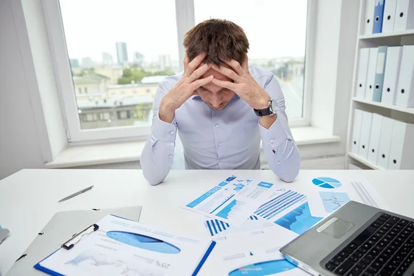 Stressad affärsman med papper i office — Stockfoto