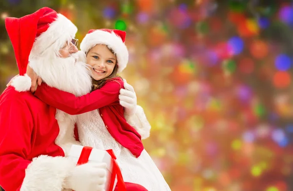 Smiling girl cuddling with santa claus over lights Royalty Free Stock Images