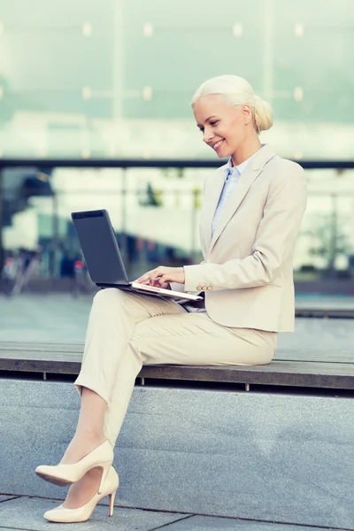 Uśmiechnięta kobieta pracuje z laptopa na zewnątrz — Zdjęcie stockowe