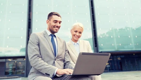 Empresários sorridentes com laptop ao ar livre — Fotografia de Stock