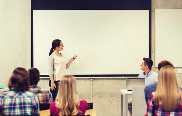 Group of students and smiling teacher in classroom — Stock Photo, Image