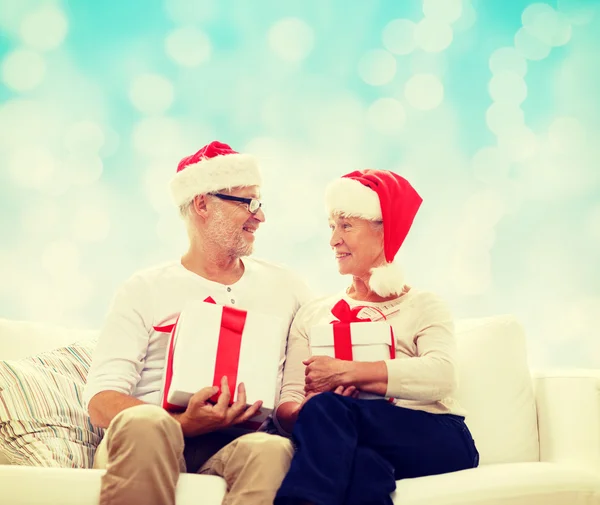 Felice coppia di anziani in cappelli di Babbo Natale con scatole regalo — Foto Stock