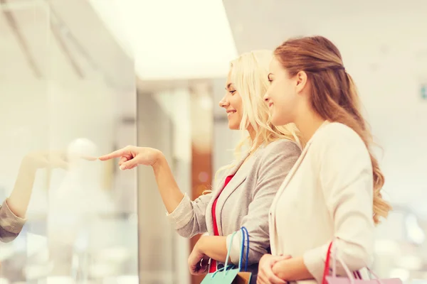 Felici giovani donne con shopping bags nel centro commerciale — Foto Stock