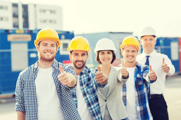 Groep van lachende bouwers in hardhats in openlucht — Stockfoto