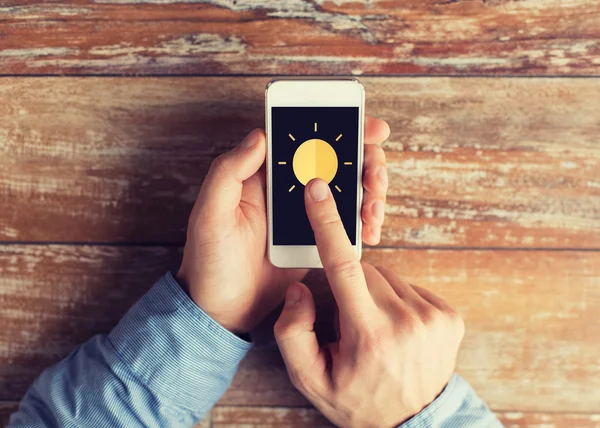 Close up of hands with sun icon on smartphone — Stock Photo, Image