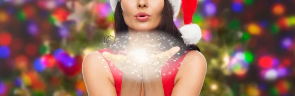 Close up of woman in santa hat blowing on palms — Stock Photo, Image