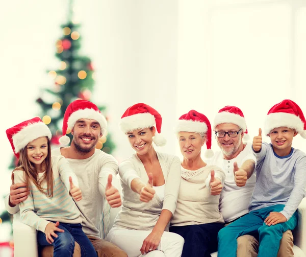 Familia feliz en sombreros de santa mostrando los pulgares hacia arriba —  Fotos de Stock