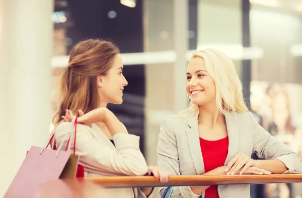 Gelukkig jonge vrouwen met boodschappentassen in winkelcentrum — Stockfoto