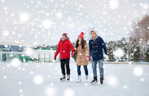 Amigos felices patinaje sobre hielo en pista al aire libre — Foto de Stock