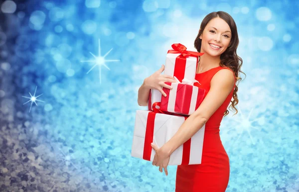 Mujer sonriente en vestido rojo con muchas cajas de regalo —  Fotos de Stock