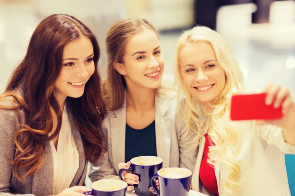 Mujeres jóvenes sonrientes con tazas y teléfono inteligente —  Fotos de Stock