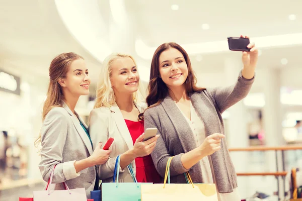 Женщины со смартфонами делают покупки и селфи — стоковое фото