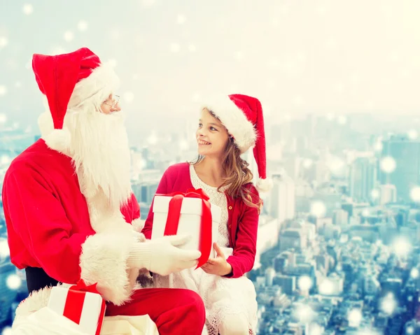 Niña sonriente con santa claus y regalos — Foto de Stock