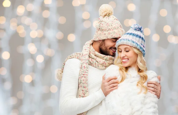 Happy couple in winter clothes hugging over lights — Stock fotografie