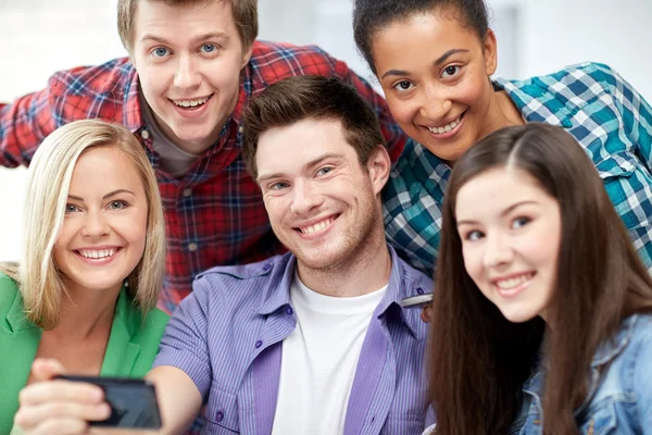 Grupo de estudiantes felices con smartphone en la escuela — Foto de Stock