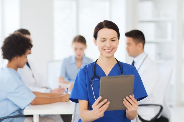 Medico felice con tablet pc sopra il team in clinica — Foto Stock