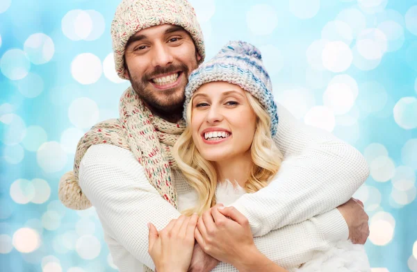 Happy couple in winter clothes hugging over lights — 스톡 사진