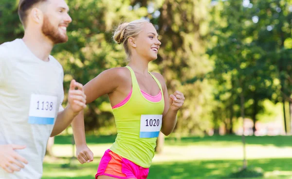 Feliz deportistas pareja carreras ingenio insignia números — Foto de Stock