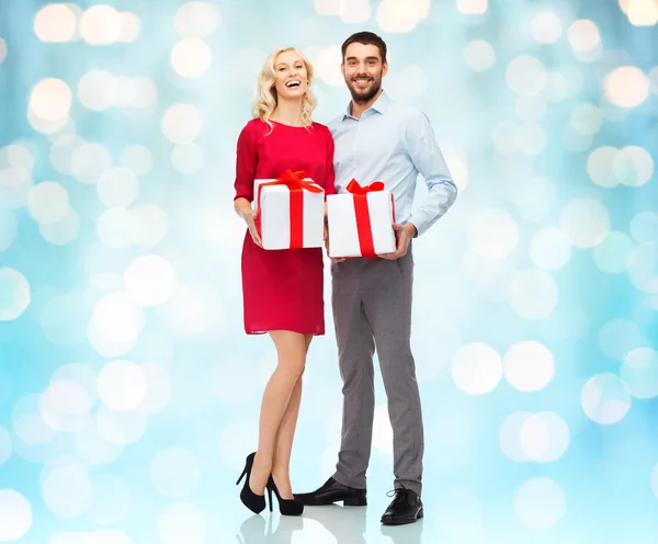 Happy couple with gift boxes over lights — Stockfoto