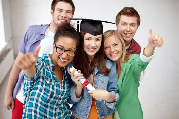 Smiling students with diploma showing thumbs up — Stock Photo, Image