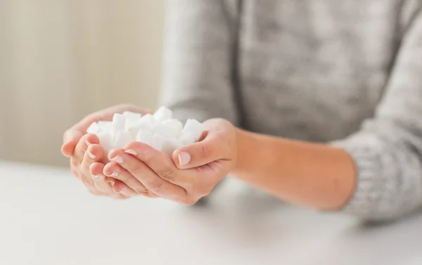 Cerca de azúcar terrón blanco en manos de la mujer — Foto de Stock
