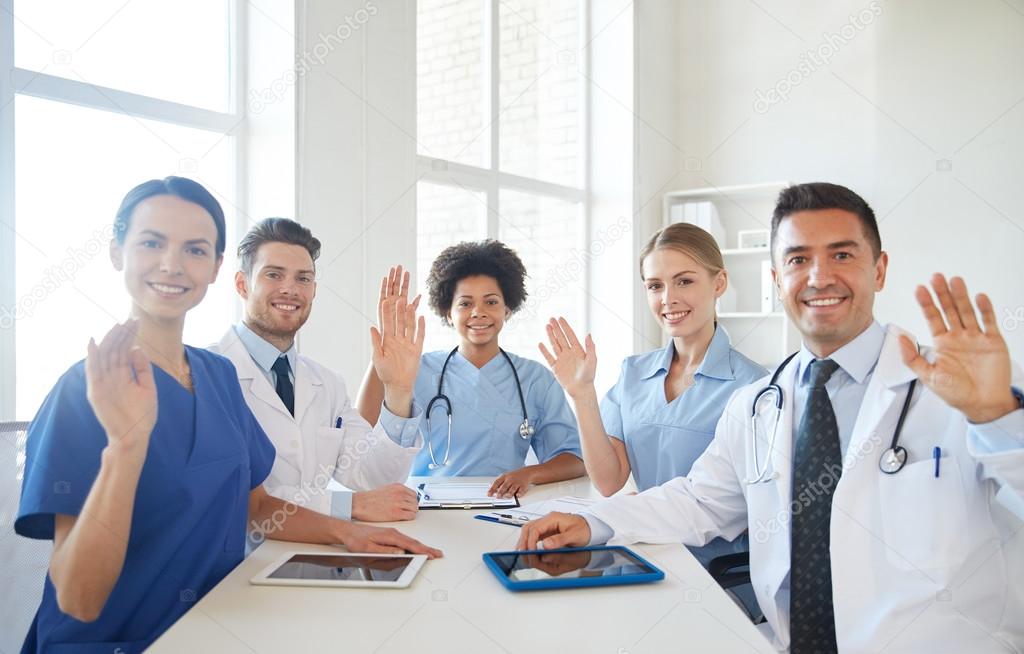 Happy doctors meeting and waving hands at hospital — Stock Photo © Syda_Productions 86747110