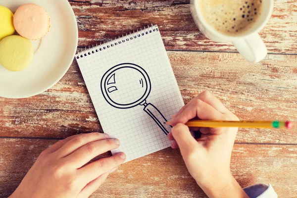 Närbild på händerna ritning förstoringsglas i anteckningsboken — Stockfoto