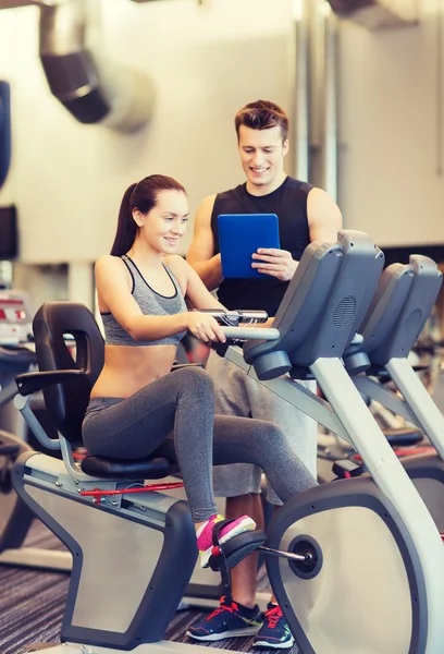 Mujer feliz con entrenador en bicicleta estática en el gimnasio — Foto de Stock