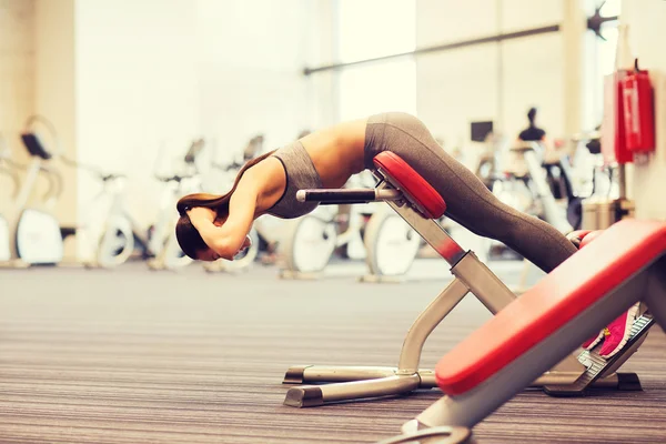 Junge Frau lässt Rückenmuskeln auf Bank im Fitnessstudio spielen — Stockfoto