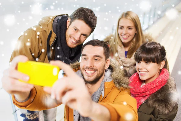 Amici felici con smartphone sulla pista di pattinaggio — Foto Stock