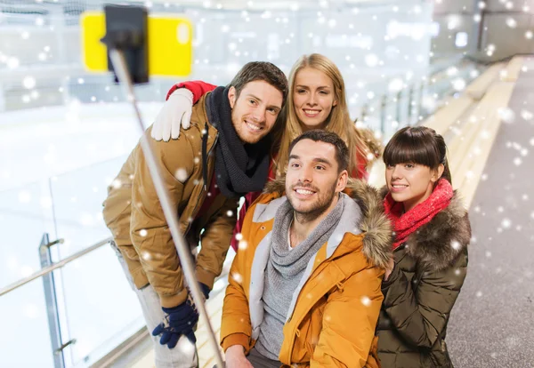 Amici felici con smartphone sulla pista di pattinaggio — Foto Stock