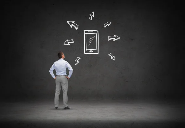 Businessman looking smartphone over concrete wall — Stock Photo, Image