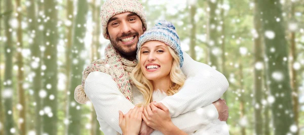 Happy couple in winter clothes hugging over forest — Stok fotoğraf