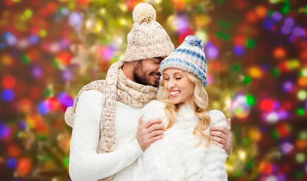 Happy couple in winter clothes hugging over lights — Stok fotoğraf