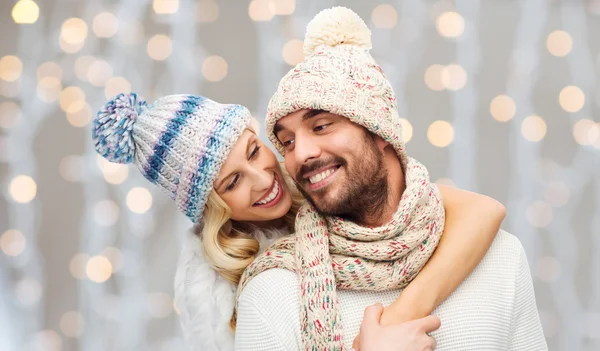 Happy couple in winter clothes hugging over lights — Stockfoto