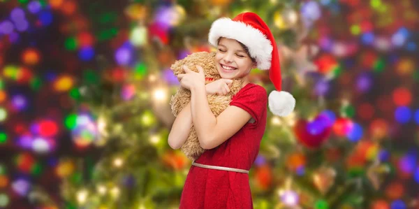 Smiling girl in santa helper hat with teddy bear — Stock Photo, Image