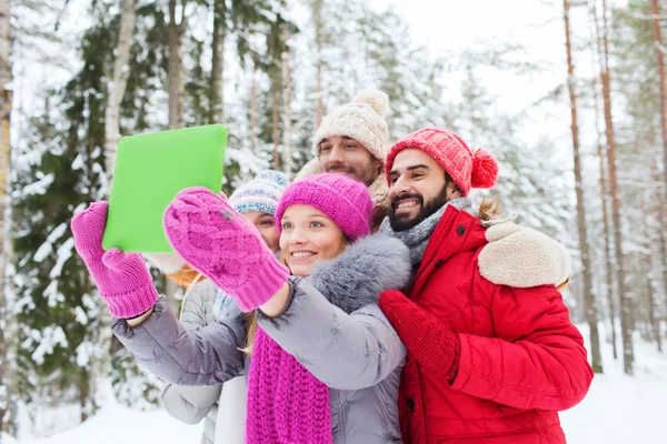 Lachende vrienden met tablet pc in winter forest — Stockfoto