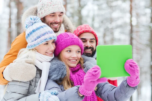 Amigos sonrientes con la tableta PC en el bosque de invierno —  Fotos de Stock