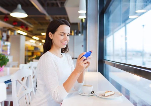 微笑与智能手机和咖啡在咖啡厅的女人 — 图库照片