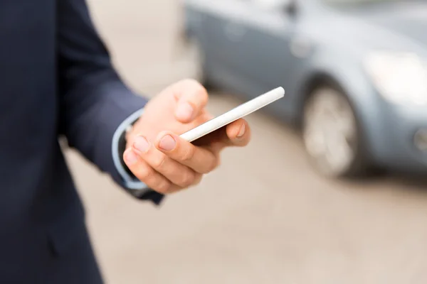 Close up of man hand with smartphone and car — Stock Photo, Image