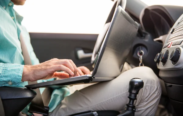Κοντινό πλάνο νεαρός άνδρας με φορητό υπολογιστή, οδήγηση αυτοκινήτου — Φωτογραφία Αρχείου