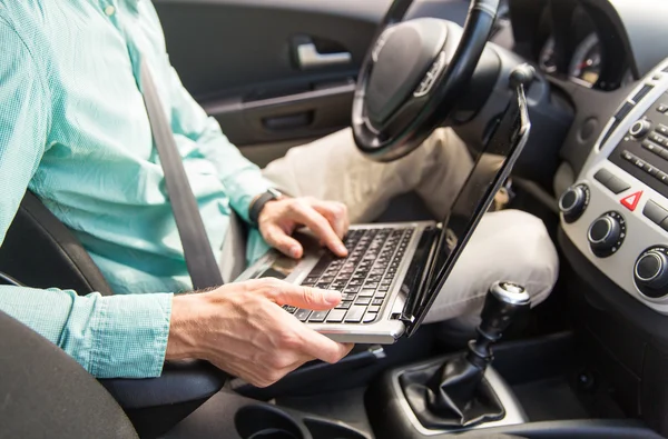 Close up van jonge man met laptop rijden auto — Stockfoto