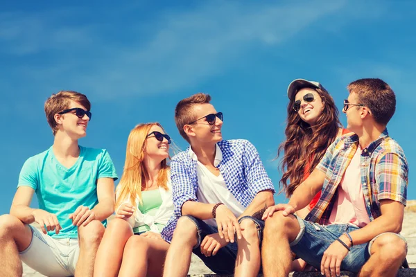 Group of smiling friends sitting on city street — Stock Photo, Image