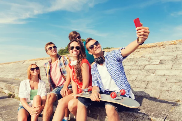 Grupa przyjaciół uśmiechający się z smartphone na zewnątrz — Zdjęcie stockowe
