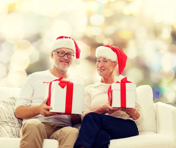 Happy senior couple in santa hats with gift boxes — Stock Photo, Image