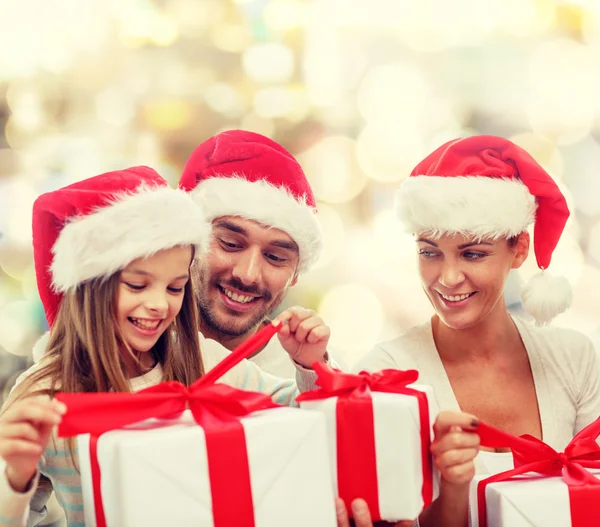 Happy family in santa hats sitting with gift boxes — Stock Photo, Image