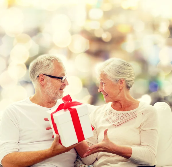 Felice coppia anziana con scatola regalo a casa — Foto Stock