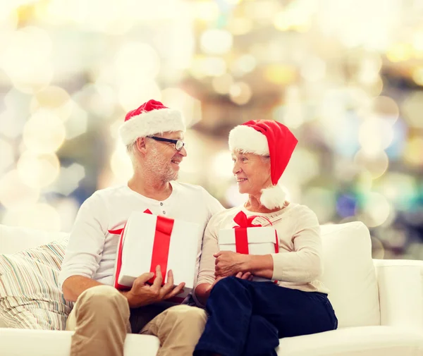 Gelukkig senior koppel in santa hoeden met geschenkdozen — Stockfoto